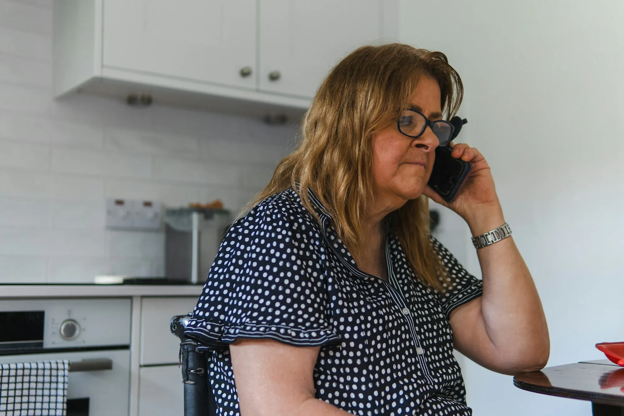 A woman taking a call on her phone in a kitchen